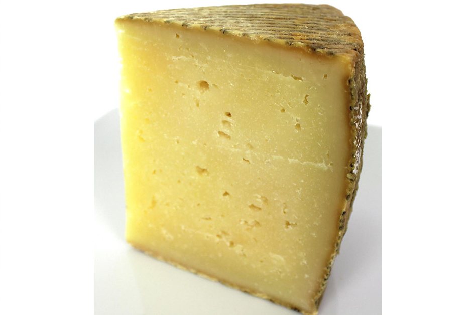 Cuña de queso curado con corteza de pleita sobre un plato blanco