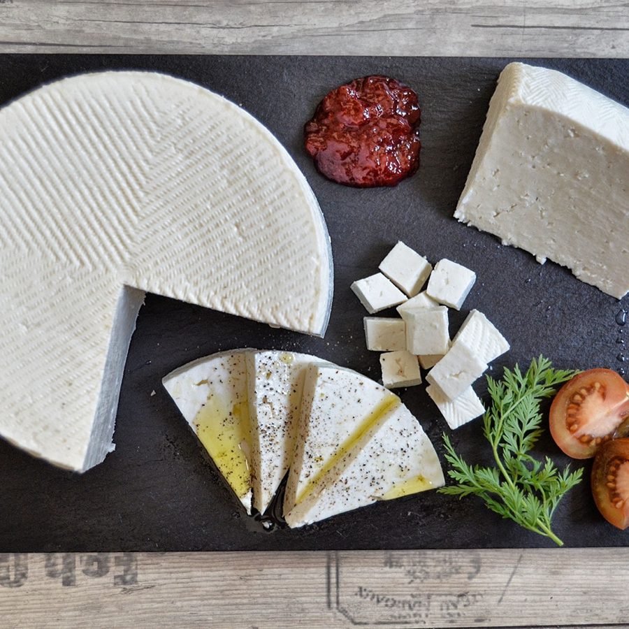 Queso fresco en rueda, en cuña, en dados y en láminas con aceite, sobre pizarra